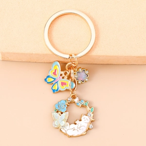 Detailed close-up of golden enamel cat, blue rose, and butterfly floral keychain pendant
