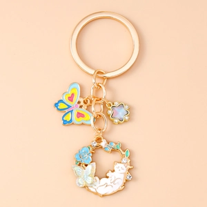 Close-up of golden keychain with enamel butterfly, star charm and floral cat wreath detail