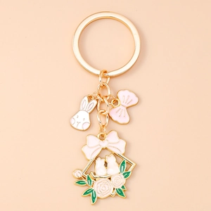 Detail of enamel flower rabbit keychain with pink bow and gold metal cat charm