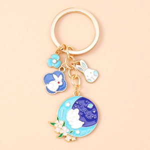 Detailed close-up of golden enamel rabbit keychain with blue flower and moon charms