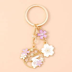 Detailed macro view of enamel rabbit and cherry blossom keychain with gold-plated finish