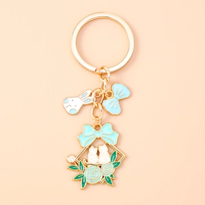 Detail of flower bunny keychain featuring blue enamel bow and cat charms on gold link