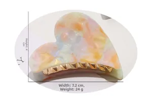 Detail of heart hair claw clip in acetate marble finish with 7.2cm by 4cm dimensions