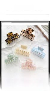 Flat lay of six acetate hair claws in various marble patterns on white fabric background