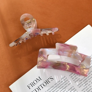 French style marbled acetate claw clips in pink and cream white on a textile background