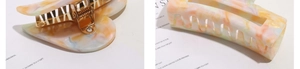 Detail of a large heart-shaped hair claw clip with colorful marble acetate patterns