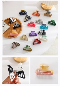Detail of hollow hair claw clips with rhinestones and marble patterns on a white table