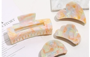 Detail of four acetate hair claws in heart and cloud shapes with marble macaron patterns