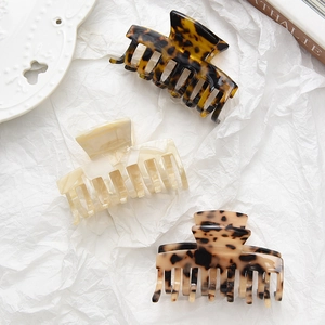 Three acetate hair claws with tortoiseshell and marble patterns on white background