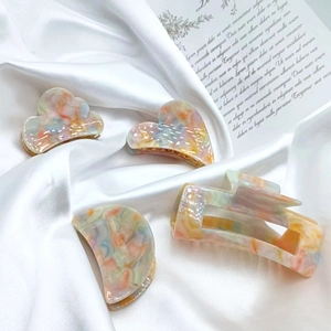 Set of four colorful acetate hair clips with marble pattern on white silk fabric