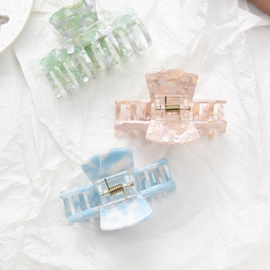 Three acetate hair claws with marble textures in green, pink, and blue colors