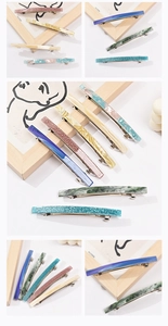 Detail view of acetate spring hair clips with colorful marble patterns and metal fasteners