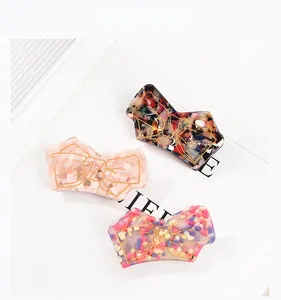 Detailed view of acetate bow hair clips with gold edging in marble and floral patterns