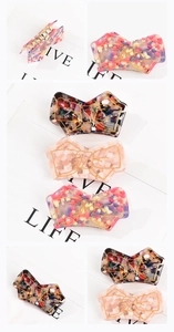 Detailed macro view of colorful mosaic acetate bow hair clips with gold-plated metal clips