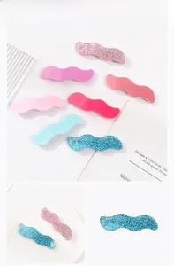 Close-up of wavy acrylic hair clips in vibrant pink and blue with glittery finish
