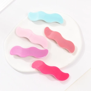 Set of wavy acrylic hair clips in five pastel colors on a white minimalist tray
