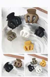 Varietà di mollette opache in colori Morandi esposte su vassoio di marmo per capelli