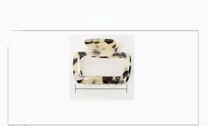 Detail view of a 6.5cm acetate hair claw clip with amber tortoiseshell pattern texture