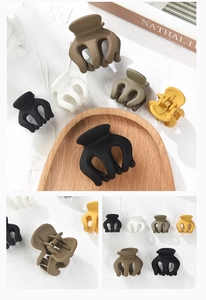 Dettaglio di mollette per capelli opache in toni terra su un vassoio di legno per styling