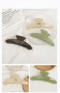 Macro detail of large acetate hair claw clips with checkered pattern and French lettering