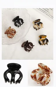 Macro detail of various tortoiseshell and marble acetate hair claws on a textured cloth