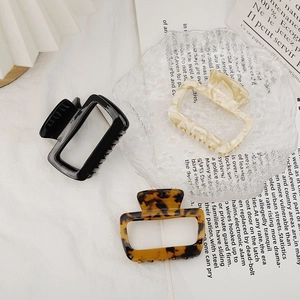 Three acetate hair claws in black, tortoiseshell, and cream marble for stylish high ponytails