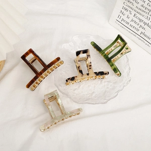 Set of four French acetate hair claws in tortoise shell and marble patterns on white linen