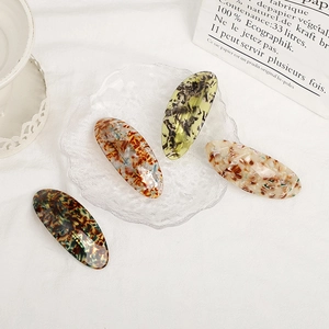 Set of four geometric acetate oval hair clips in assorted marble and tortoise patterns