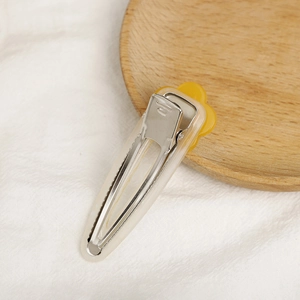 Close-up of yellow flower acetate hair clip with metal grip on a natural fabric background