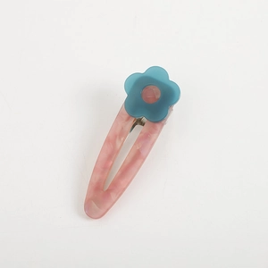 Pink marble acetate flower hair clip with blue blossom accent on white background
