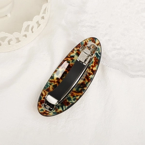 Elegant oval acetate hair barrette with vintage tortoiseshell pattern on white fabric