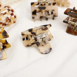 Acetate checkered hair claw clip set with tortoiseshell pattern on white fabric