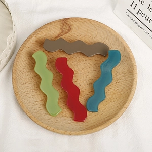 Minimalist wavy acetate hair clips in matte candy colors displayed on wooden tray