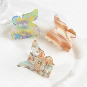 Three acetate butterfly hair claws in colorful marble patterns on a white tray