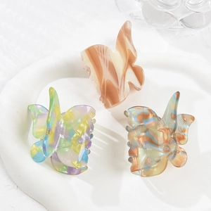 Detail view of butterfly acetate hair claws in assorted marble patterns on ceramic tray