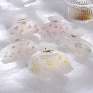 Détail de pinces à cheveux en acrylique à motifs floraux et cœurs avec ressort en métal