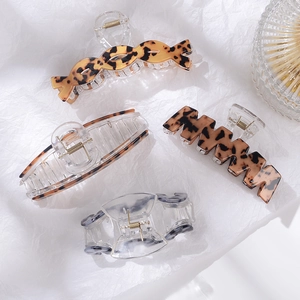Flat lay of assorted leopard print and clear acrylic hair claws on white paper