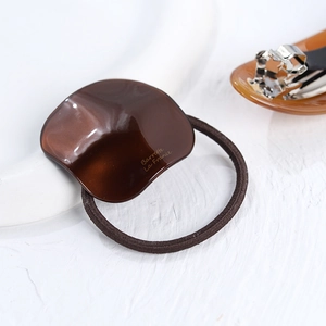 Elegant dark brown oval acetate hair tie with Barrette La France text and elastic cord