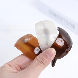 Close-up of acetate resin ponytail clips in amber, pearl white, and dark brown finishes
