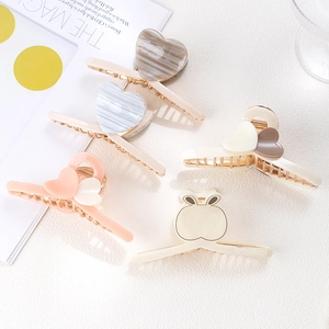 Detailed showcase of heart-shaped acetate and metal hair claws on a textured surface