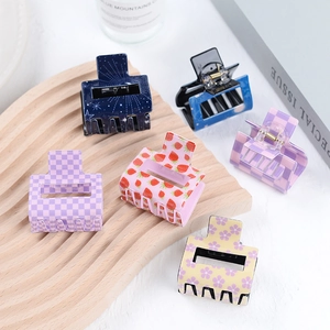 Set of colorful square acrylic hair claws with diverse patterns on a wooden tray