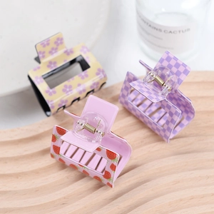 Detail of square acrylic hair claws with purple checkerboard, floral and strawberry patterns