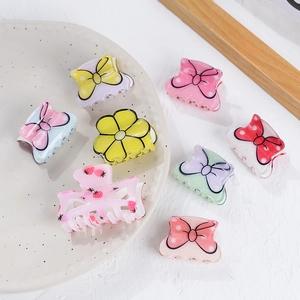 Detailed close-up of colorful butterfly and flower acrylic hair clips on ceramic tray