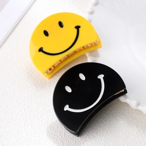 Détail de pinces à cheveux semi-circulaires en acrylique jaune et noir avec motif souriant