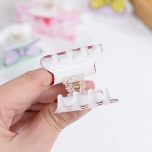 Floral print acrylic hair claw clip with sweet heart pattern held in hand