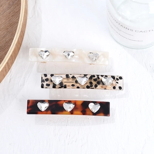Close-up of acetic acid hair clips with heart-shaped rhinestones and unique patterns