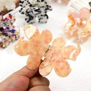 Elegant floral acetate hair claw clip with warm orange marble texture and metal spring