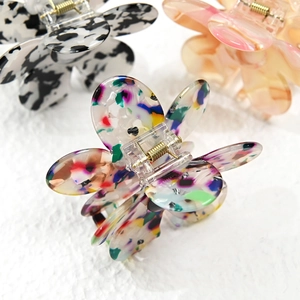 Detailed view of flower-shaped hair claws with acrylic gradient and marble texture patterns