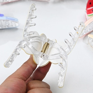 Detailed macro view of large acrylic hair claw clip with butterfly inlay and metal spring