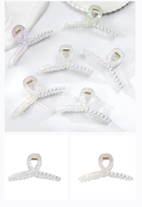 Macro shot of elegant hair claw clip with iridescent pearls and twisted resin design